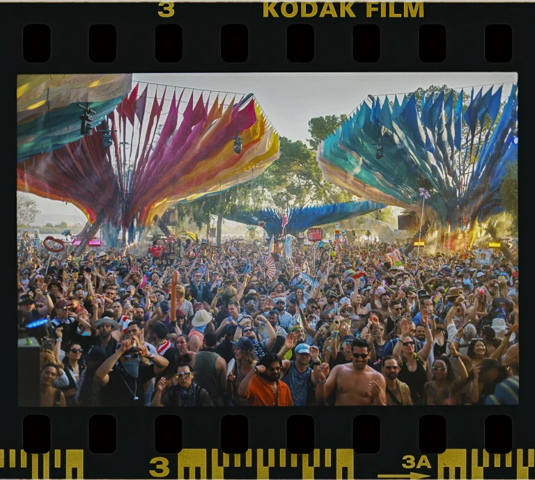Lightning in a Bottle festival crowd gathered around a large outdoor stage.