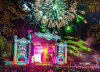 Colorful Electric Forest festival scene with lights, stage design, and people moving through the grounds.